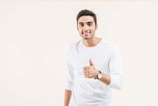 happy young man showing thumb up and smiling at camera isolated on beige  - Foto, Imagem