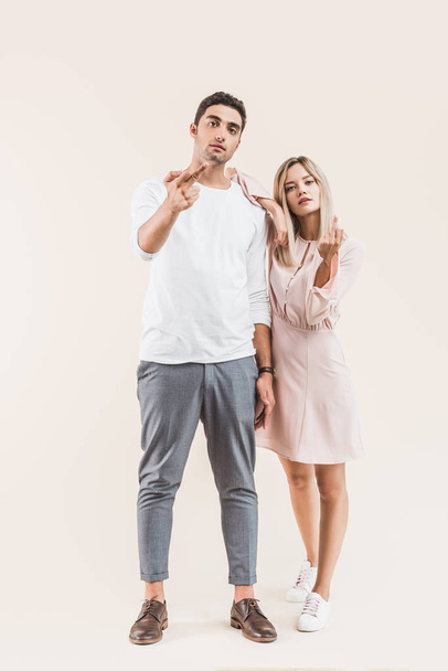 aggressive young couple giving the fingers and looking at camera isolated on beige - Photo, Image