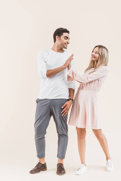 happy young couple giving high five and smiling each other isolated on beige - Foto, immagini