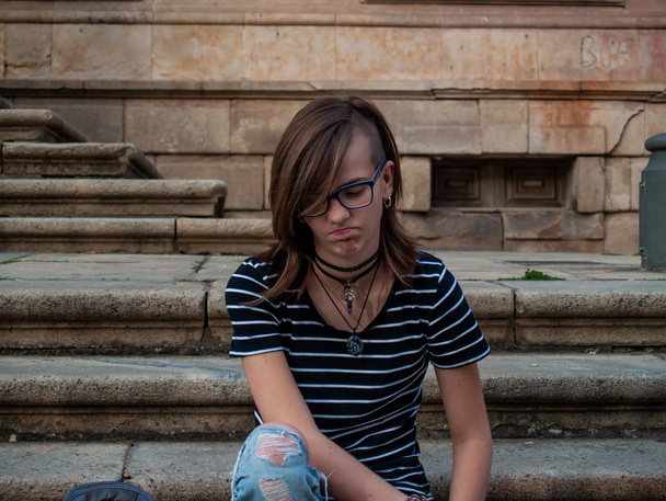 Uma adolescente gesticulando nas escadas de um prédio antigo em um campus universitário
 - Foto, Imagem