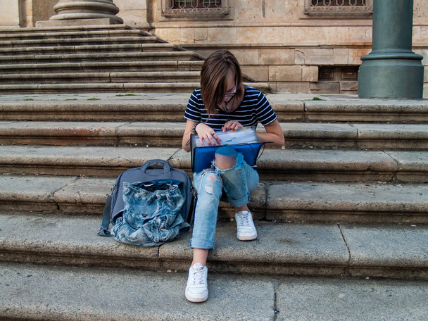 Eine junge Frau studiert mit einem Bindemittel auf der Treppe einer Universität auf einem Universitätscampus - Foto, Bild