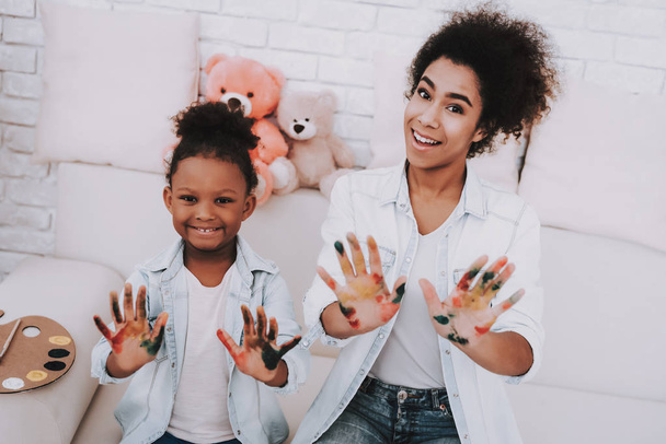 Relaxation with Mother and Daughter. Mulatto with Mother. Helping Girl with Paint. Young Girl With Mother Paint Hand. Color in Hand. Happy Girl and Happy Mother. Exercise for Mother. Mother Help Girl. - Φωτογραφία, εικόνα