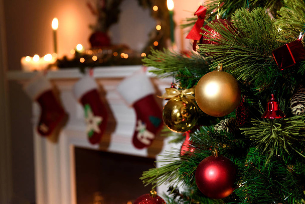Mooi ingericht open haard en een kerstboom in cottage. Een rijke kerstboom met veel opknoping speelgoed en een gehulde open haard op de achtergrond wazig - Foto, afbeelding