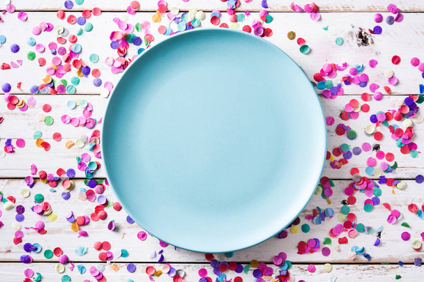 Colorful confetti and blue plate on white wooden background. Top view - Fotoğraf, Görsel