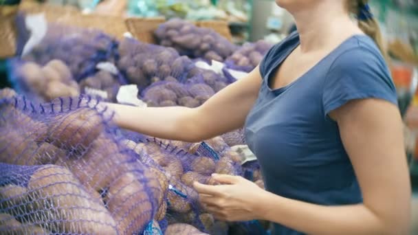A woman in a supermarket buying vegetables, potatoes. - Felvétel, videó