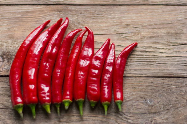 lusky červené chilli papričky na dřevěné pozadí - Fotografie, Obrázek