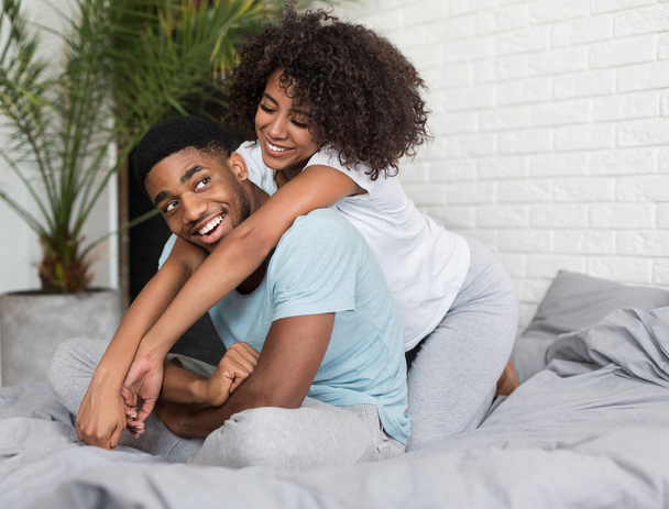 Любящая молодая черная пара, обнимающая в постели
 - Фото, изображение