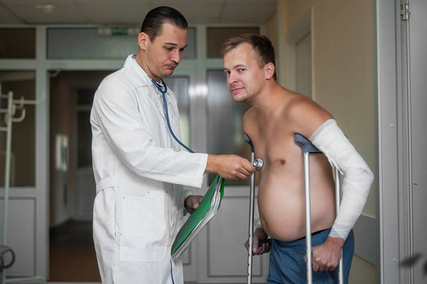 Чоловік-лікар слухає клієнта за допомогою стетоскопа в лікарні
 - Фото, зображення