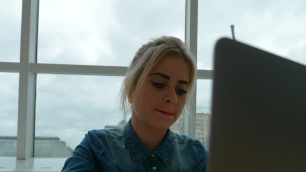 Mulher trabalhando no laptop no cafe.A menina loira acha que ela deve escrever
. - Filmagem, Vídeo