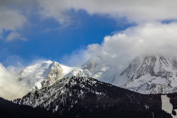 Impresionante vista aérea del pico de la montaña del Mont Blanc cubierto de nieve brillante, hielo y glaciares bajo el cielo azul con nubes blancas hinchadas en el lado francés de los Alpes en un día de invierno claro y soleado
 - Foto, Imagen