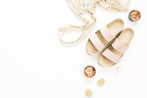 Mulher estilo ouro composição da moda com chinelos, saco de cordas, brinco e anéis no fundo branco. Deitado plano, vista superior
. - Foto, Imagem