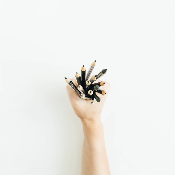 Vrouw hand hebt stelletje potloden op witte achtergrond. Plat lag, top uitzicht minimal kunstenaar samenstelling. - Foto, afbeelding