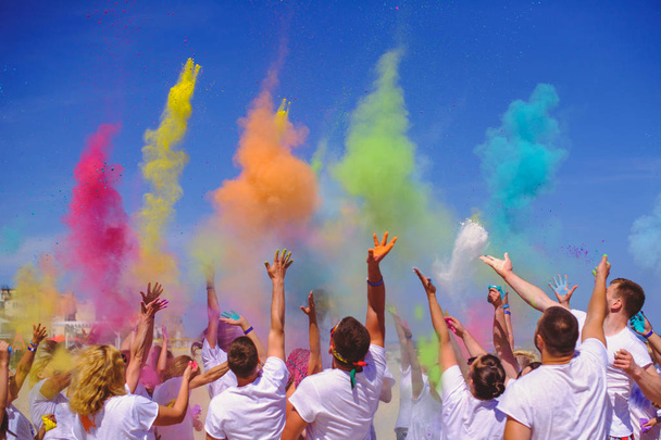 brillante La gente celebra la fiesta Holi, un grupo de personas arrojan pintura en el cielo azul
. - Foto, Imagen
