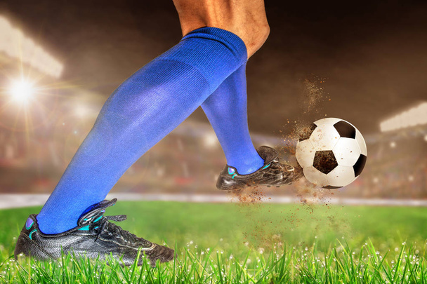 Ποδοσφαιριστής σε δράση με το ποδόσφαιρο σε φωτεινά υπαίθριο γήπεδο. Επικεντρωθεί σε πρώτο πλάνο και το ποδόσφαιρο μπάλα με ρηχό βάθος πεδίου στο φόντο και αντίγραφο χώρου. - Φωτογραφία, εικόνα