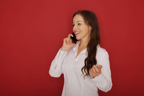 Portrait of smiling business woman phone talking, isolated on red background - Zdjęcie, obraz
