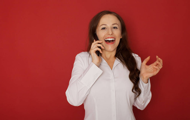 Portret uśmiechnięty telefon służbowy Kobieta, mówić na białym tle na czerwonym tle - Zdjęcie, obraz