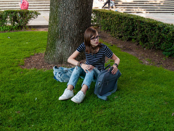 Une adolescente étudiant avec un ordinateur portable assis sur l'herbe dans un parc d'une université dans un campus universitaire
 - Photo, image