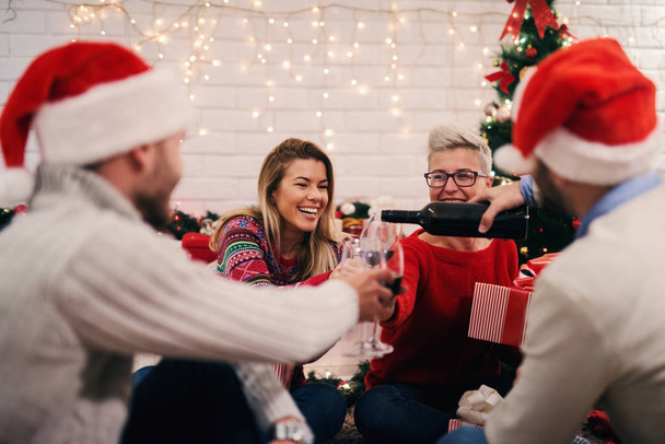 Genç mutlu arkadaşlar kutlama Noel evde parti, kadehlerin şarap dökme - Fotoğraf, Görsel