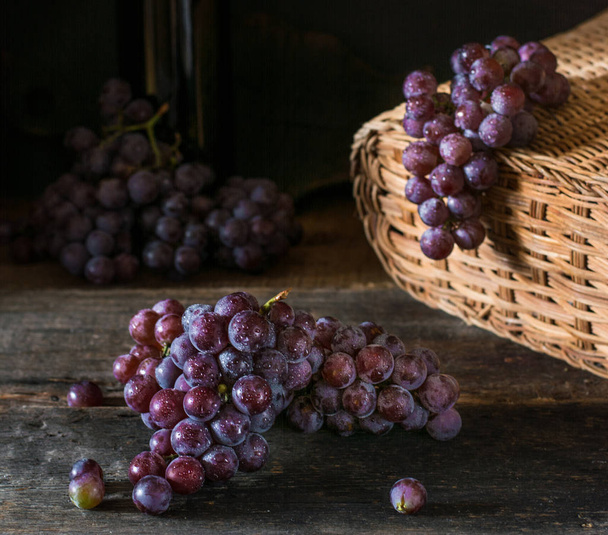 Bunches of fresh ripe red grapes on a wooden textural surface. Branch of pink grapes. Red wine grapes. dark grapes. Still life of food. Nature. Autumn harvest. Vegetarian nutrition. Winery. - Photo, Image