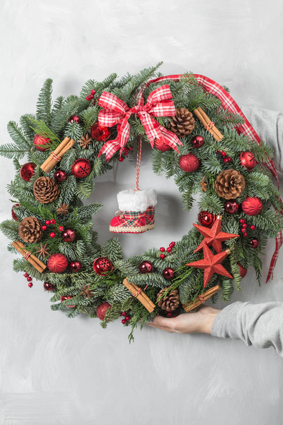 Preparation for holidays concept. Beautiful Christmas wreath in woman hands. Flower shop is a master work of a professional florist. - Photo, Image