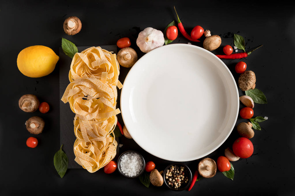 Fettuccine tagliatelle plakken en witte plaat met paddenstoelen, kruiden en specerijen - Foto, afbeelding