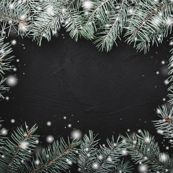 黒正方形石の背景。モミの枝のフレームです。雪の効果。テキストのためのスペース。トップ ビュー - 写真・画像