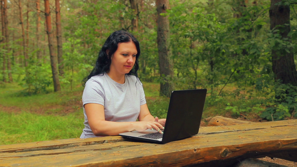 fiatal nő, egy parkban a gépelés-ra egy laptop. - Felvétel, videó