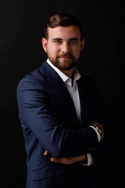 Close-up portrait of an attractive businessman with a beard an elegant suit on a black background. The concept of a success and business. - Fotografie, Obrázek
