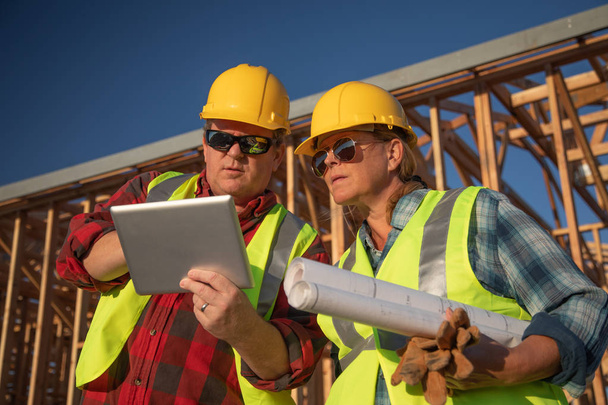 Erkek ve dişi inşaatı işçi inşaatı sitesinde bilgisayar panelini kullanma. - Fotoğraf, Görsel
