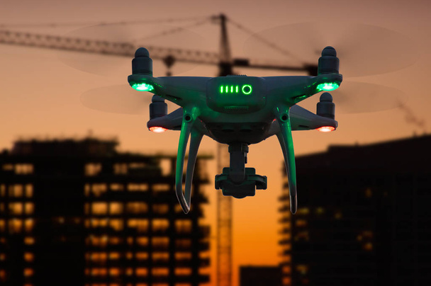 Силует безпілотних літальних апаратів системи (БЛА) Quadcopter Drone в повітрі над будівель під будівництво. - Фото, зображення