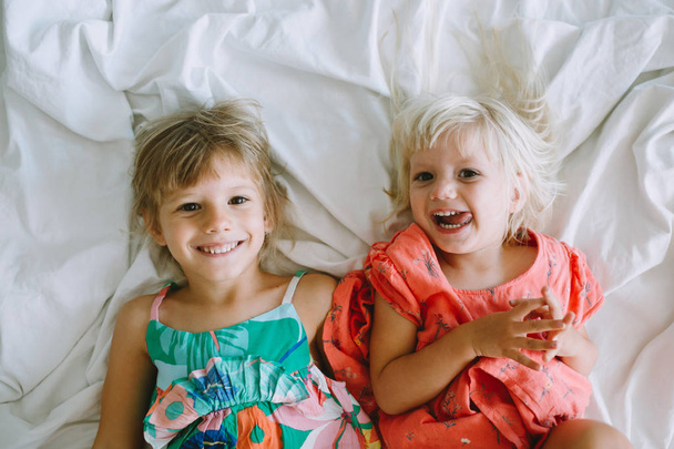 2 人のかわいい姉妹ベッドで横になっていると笑っています。 - 写真・画像