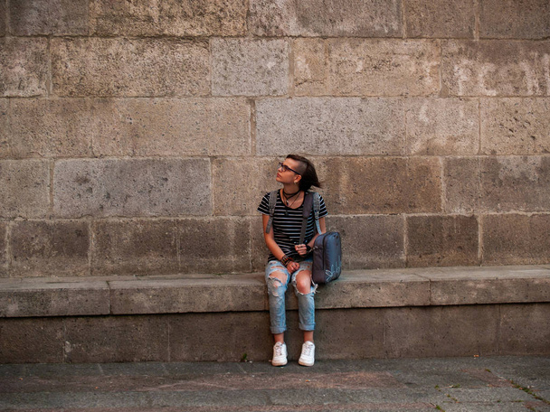 Подростковая женщина, сидящая перед стеной и отдыхающая
 - Фото, изображение