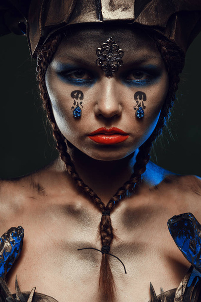 Beautiful and emotional girl on a dark background in the studio with a terrible makeup for Halloween - Фото, изображение