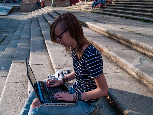 Eine junge Frau studiert mit einem Laptop auf der Treppe einer Universität in einem Universitätscampus - Foto, Bild