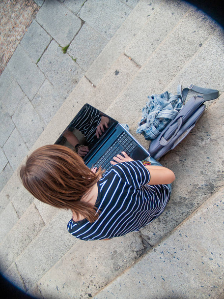 Une adolescente étudiant avec un ordinateur portable dans les escaliers d'une université dans un campus universitaire
 - Photo, image
