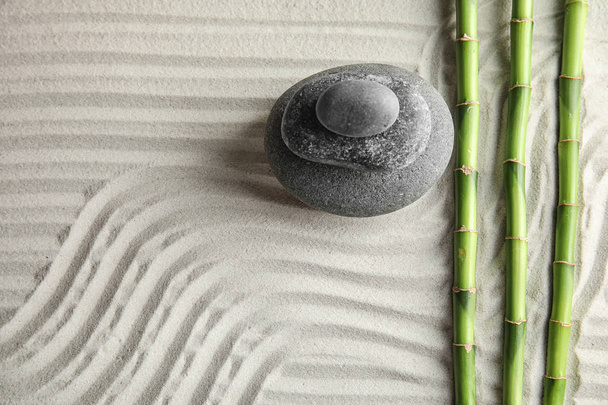 Bamboo branches with spa stones on sand, top view. Space for text - Foto, afbeelding