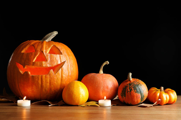 Halloween pumpkin head jack lantern and autumn decorations on table against dark background - Fotografie, Obrázek
