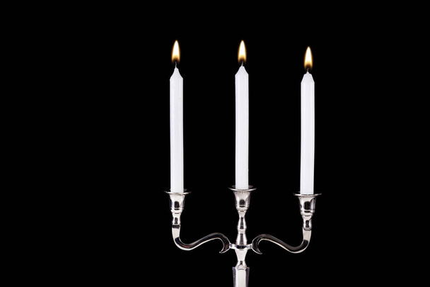 Castiçal barroco prata com velas brancas de parafina queimando isolado no fundo preto. Fechar e espaço para design e texto
 - Foto, Imagem