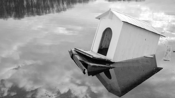 Drowning house of swans and ducks on the lake. Swan house. White house. Drowning structure. A wooden shed for swans and ducks. The smooth surface of the lake. Half-submerged shed. Water surface. The building on the lake. - Photo, Image