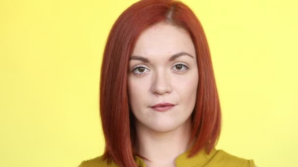 Positive red haired woman smiling at camera, posing on yellow background. - Footage, Video