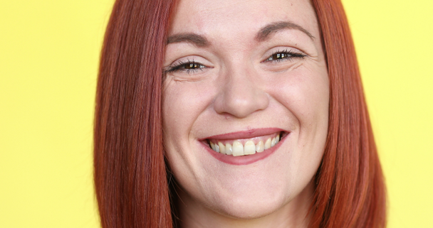 肯定的な赤い髪の女性、カメラに笑顔黄色の背景でポーズ. - 映像、動画