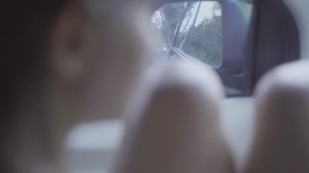 Πορτρέτο της νεαρής γυναίκας με γυμνά γόνατα κάθεται σε κινείται το αυτοκίνητο, κοιτάζοντας καθρέφτη - Πλάνα, βίντεο
