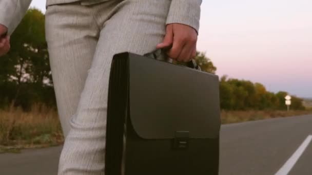 üzletasszony, a kezében, nadrág és zakó az aszfalton, a goes fekete táska közelről - Felvétel, videó