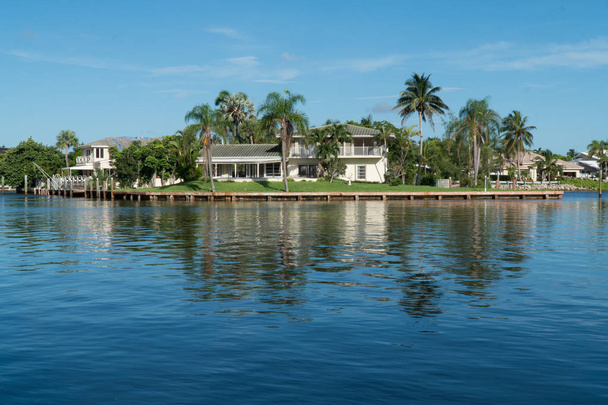 Tagesaussenaufnahme der generischen Villa entlang des Flusses in tropischer Insellage. Palmen und ruhiges Wasser im Hinterhof des Luxus-Hauses in schönen Sommer-Destination - Foto, Bild
