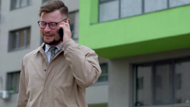 Cheerful businessman talking on his phone outdoors. - Video
