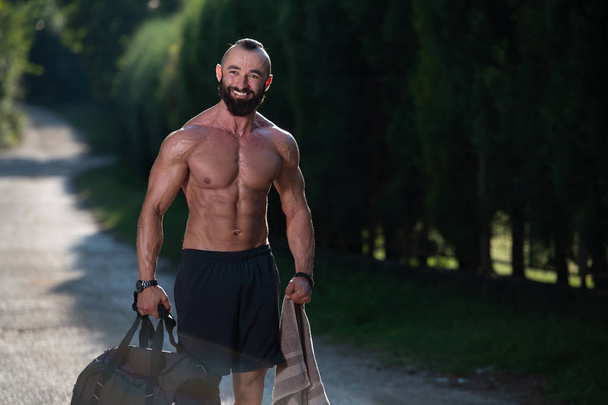 Beard Man Wearing a Sports Bag Outdoors in Park and Is Going to Fitness Center in Gym - Fotó, kép
