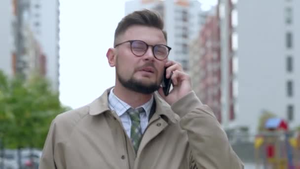 Cheerful businessman talking on his phone outdoors. - Záběry, video