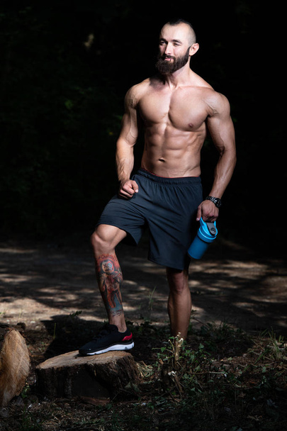 Beard Muscular Man Resting After Exercise Outdoors And Drinking From Shaker - Foto, Bild