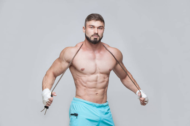 Sport, activity. Muscular Fighter kickbox with skipping rope. Muscular men grey background. - Photo, image