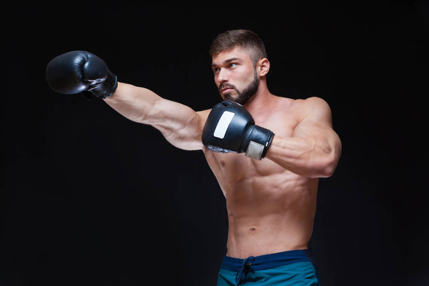 Strong muscular boxer in black boxing gloves. Isolated on black background. - Foto, Imagem